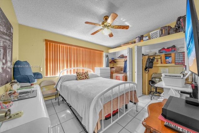 bedroom with ceiling fan, a closet, light tile patterned flooring, and a textured ceiling