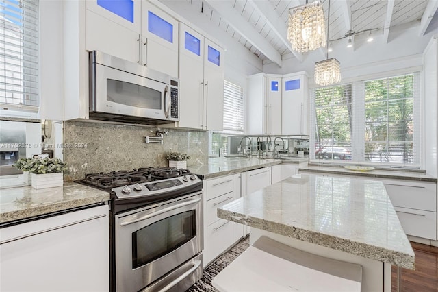 kitchen featuring pendant lighting, an inviting chandelier, beam ceiling, white cabinetry, and stainless steel appliances