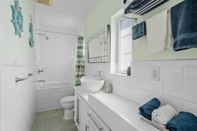 full bathroom with shower / bathtub combination with curtain, tile patterned floors, toilet, vanity, and tile walls