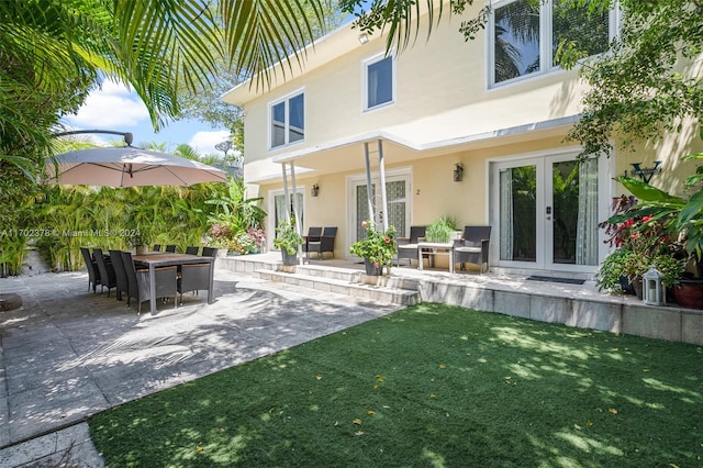 back of property with a lawn, a patio area, and french doors