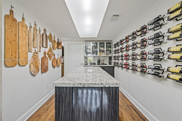 kitchen featuring a kitchen island, dark hardwood / wood-style flooring, and light stone countertops