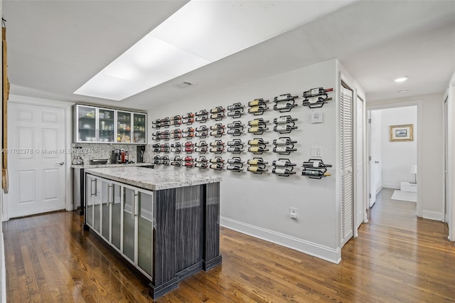 kitchen with backsplash, dark hardwood / wood-style floors, and light stone counters