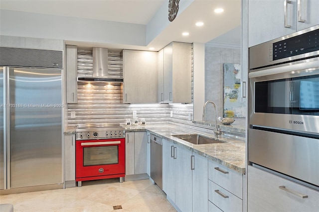 kitchen featuring sink, tasteful backsplash, premium appliances, light stone countertops, and wall chimney range hood