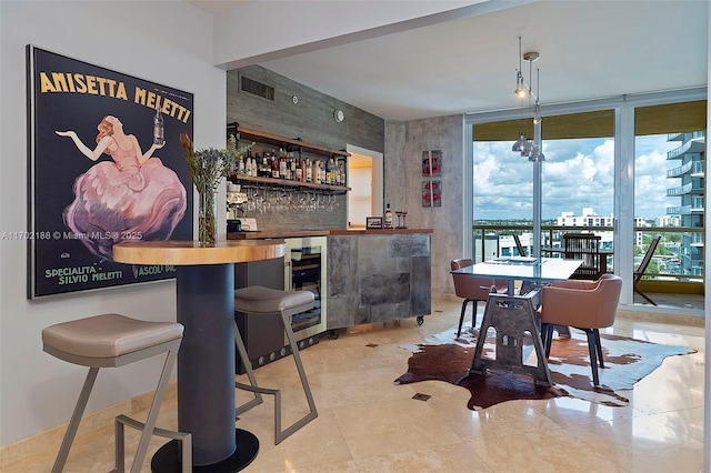 bar with pendant lighting, a wall of windows, and beverage cooler