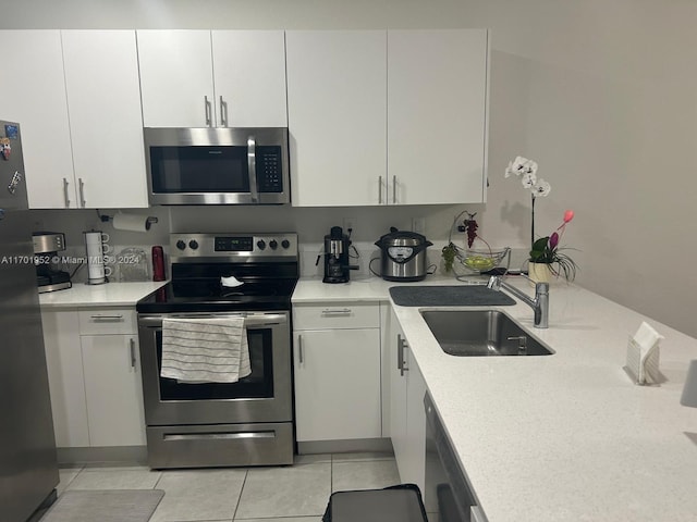 kitchen featuring white cabinets, sink, light tile patterned floors, and stainless steel appliances