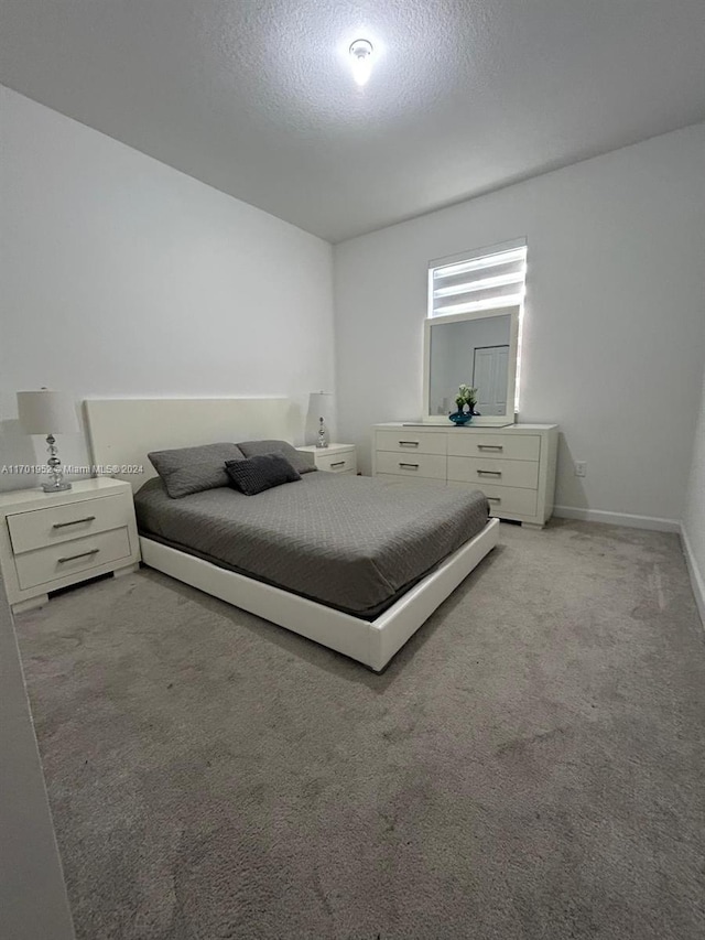 bedroom featuring light colored carpet and a textured ceiling