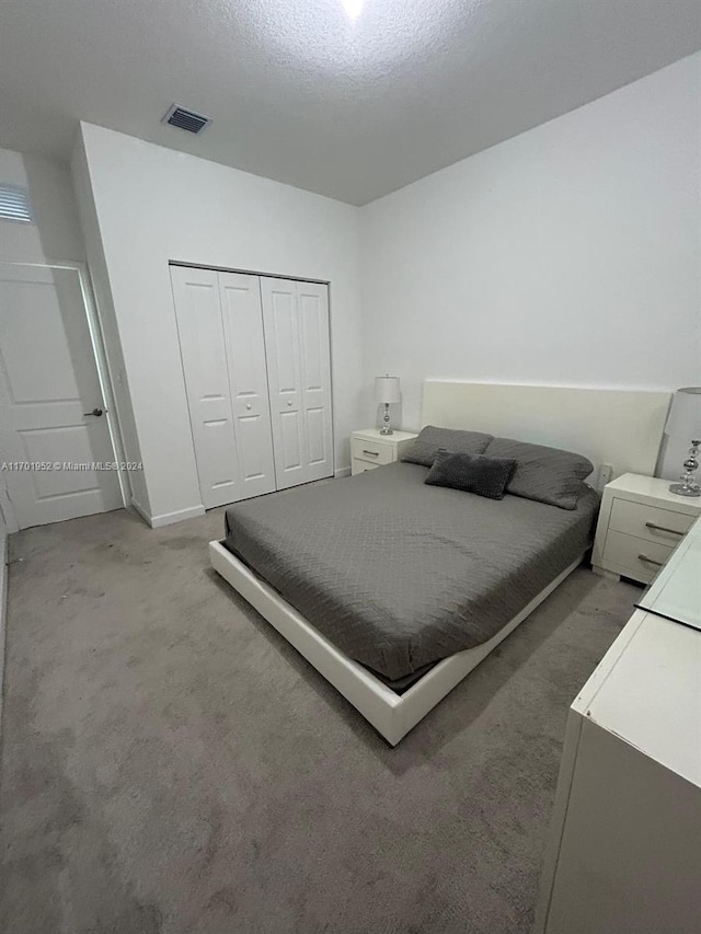 bedroom with a textured ceiling, carpet floors, and a closet