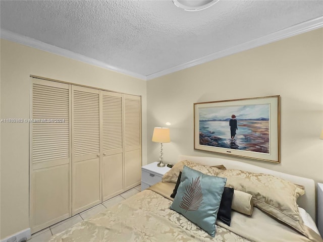 tiled bedroom featuring a textured ceiling, a closet, and crown molding