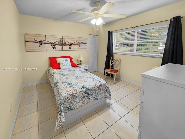 tiled bedroom with ceiling fan and a closet