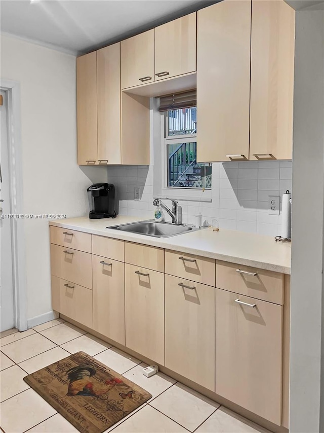 kitchen with light brown cabinetry, decorative backsplash, sink, and light tile patterned floors