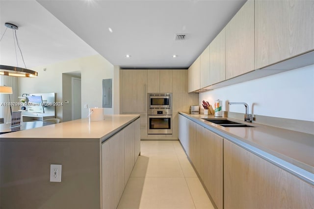 kitchen with a center island, light brown cabinets, sink, decorative light fixtures, and stainless steel appliances