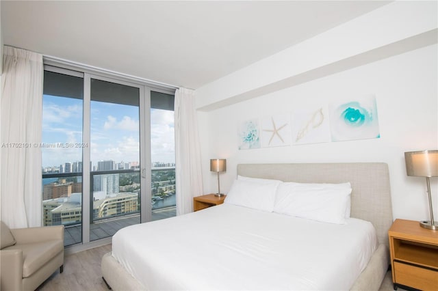 bedroom with floor to ceiling windows, access to exterior, and light wood-type flooring