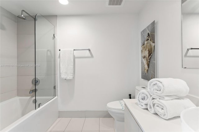 bathroom featuring tile patterned flooring, tiled shower / bath combo, and toilet