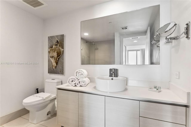 bathroom with tile patterned flooring, a tile shower, vanity, and toilet