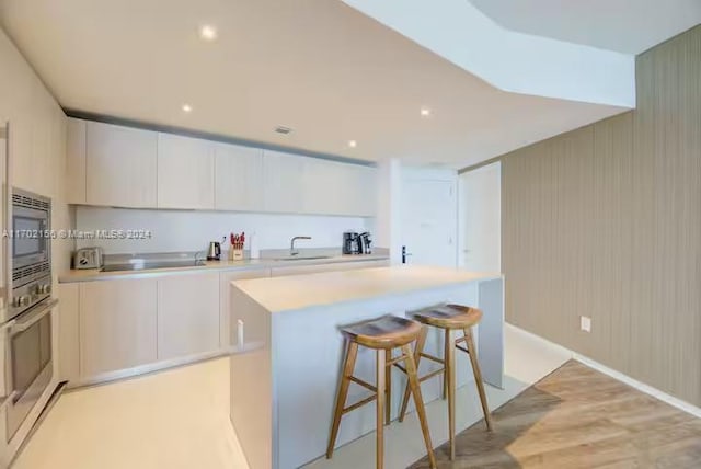 kitchen featuring a center island, stainless steel appliances, white cabinetry, and light hardwood / wood-style floors