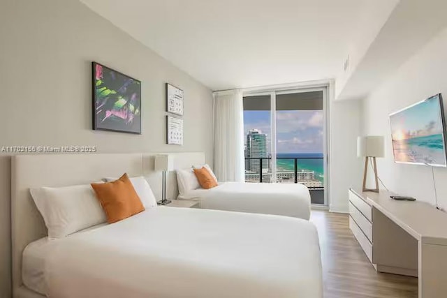 bedroom with access to exterior, light wood-type flooring, and expansive windows