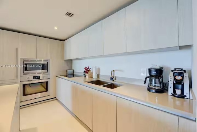 kitchen with white cabinets, appliances with stainless steel finishes, light countertops, and a sink