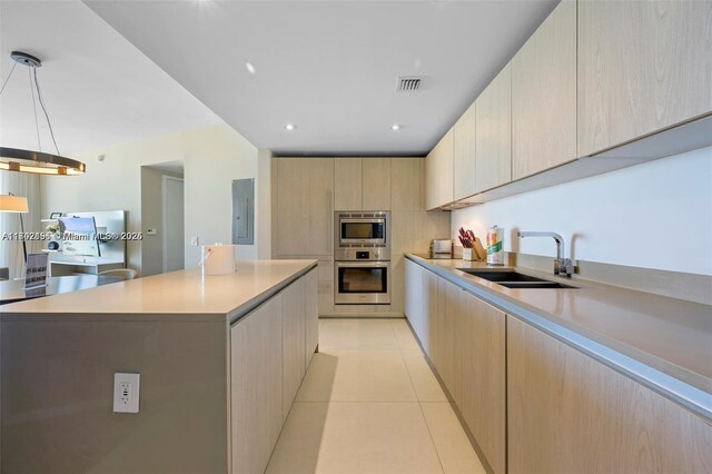 kitchen featuring a center island, sink, stainless steel appliances, pendant lighting, and light brown cabinetry