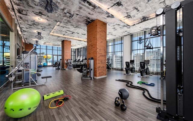 exercise room with a towering ceiling, dark hardwood / wood-style floors, and floor to ceiling windows