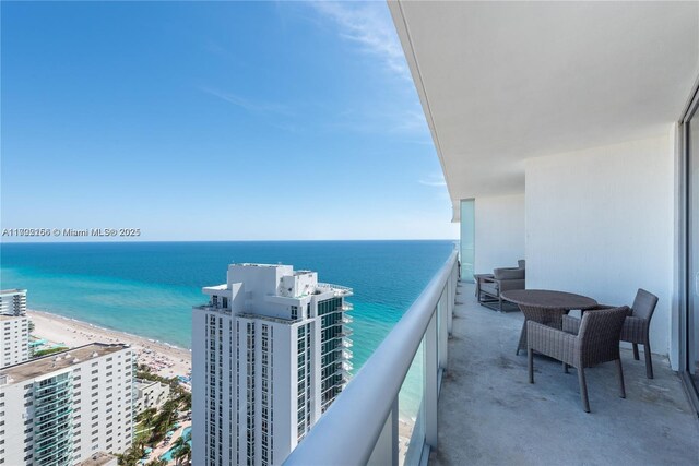 balcony with a water view and a view of the beach