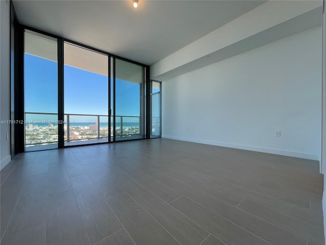 spare room featuring a wall of windows and dark wood-type flooring