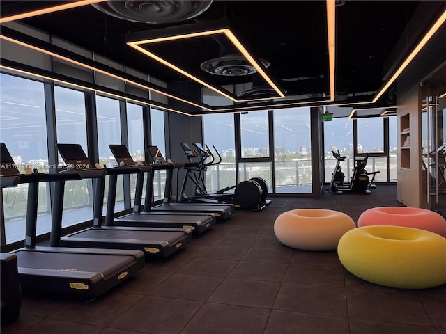 workout area with a water view, floor to ceiling windows, and a healthy amount of sunlight