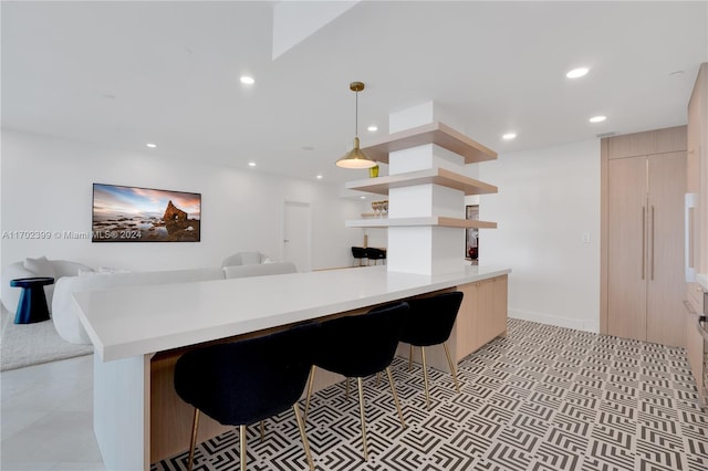 kitchen featuring pendant lighting, a breakfast bar, light brown cabinets, and kitchen peninsula