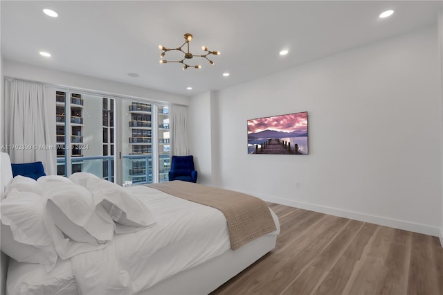 bedroom with access to outside, an inviting chandelier, and hardwood / wood-style flooring