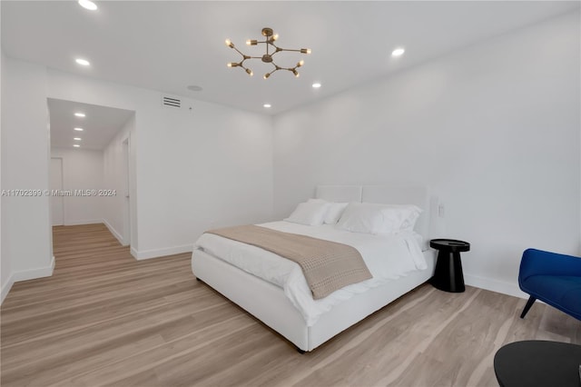 bedroom with light hardwood / wood-style flooring and a chandelier