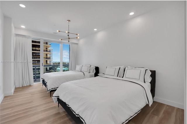 bedroom featuring access to exterior, a chandelier, and light hardwood / wood-style flooring