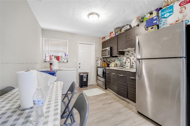 kitchen with sink, tasteful backsplash, dark brown cabinets, light hardwood / wood-style floors, and stainless steel appliances