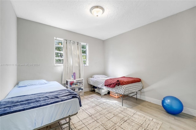 bedroom with a textured ceiling and light hardwood / wood-style flooring