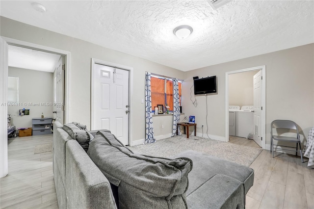 living room featuring a textured ceiling, washing machine and dryer, and light hardwood / wood-style flooring