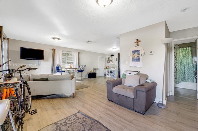 living room with a textured ceiling and light hardwood / wood-style flooring