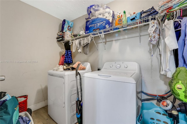 clothes washing area featuring light hardwood / wood-style flooring and washer and clothes dryer