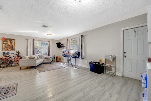 living room with a textured ceiling and light hardwood / wood-style floors