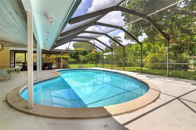 view of pool with glass enclosure and a patio area