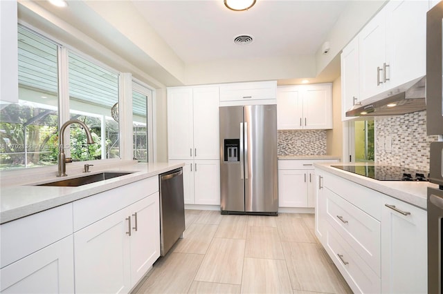 kitchen with stainless steel appliances, sink, white cabinets, and backsplash