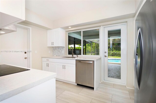 kitchen with appliances with stainless steel finishes, sink, white cabinets, and decorative backsplash