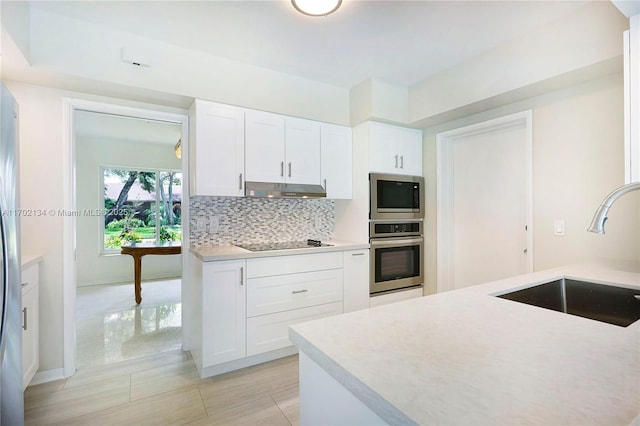 kitchen with stainless steel appliances, sink, white cabinets, and backsplash