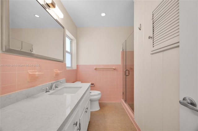 bathroom with vanity, toilet, an enclosed shower, and tile walls