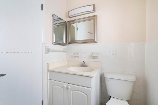 bathroom with vanity, tile walls, and toilet