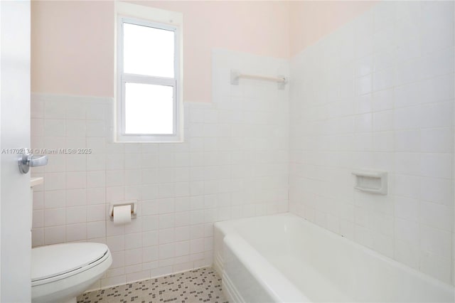 bathroom featuring tile walls, tile patterned flooring, a bathtub, and toilet