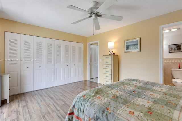 bedroom with light wood-type flooring, connected bathroom, tile walls, and ceiling fan