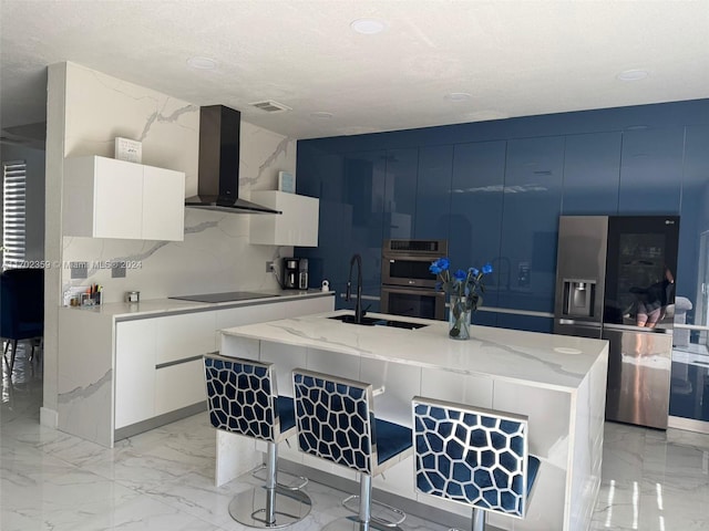 kitchen with a kitchen island with sink, white cabinets, extractor fan, and appliances with stainless steel finishes