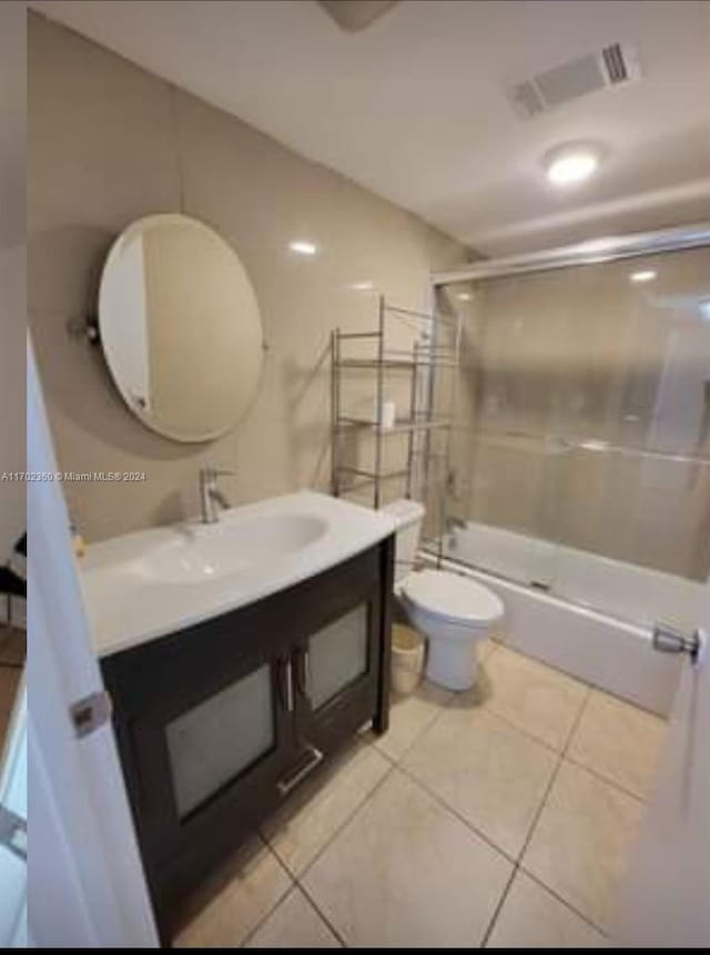 full bath featuring a shower with door, visible vents, toilet, vanity, and tile patterned flooring