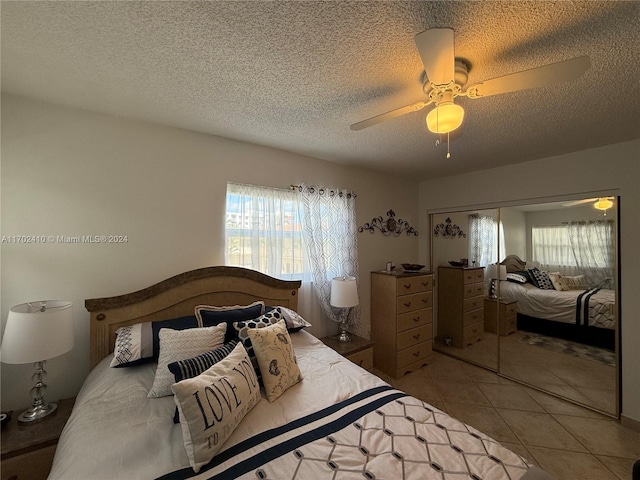 tiled bedroom featuring ceiling fan, a textured ceiling, and a closet