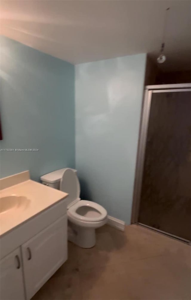 bathroom featuring vanity, toilet, and a shower with shower door