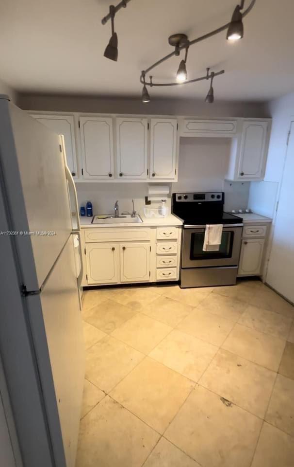 kitchen featuring sink, white cabinets, stainless steel electric range, and white refrigerator