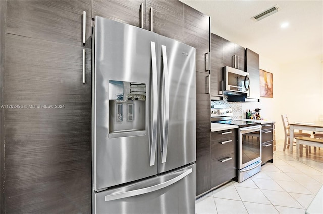 kitchen featuring appliances with stainless steel finishes, tasteful backsplash, light tile patterned floors, and dark brown cabinets